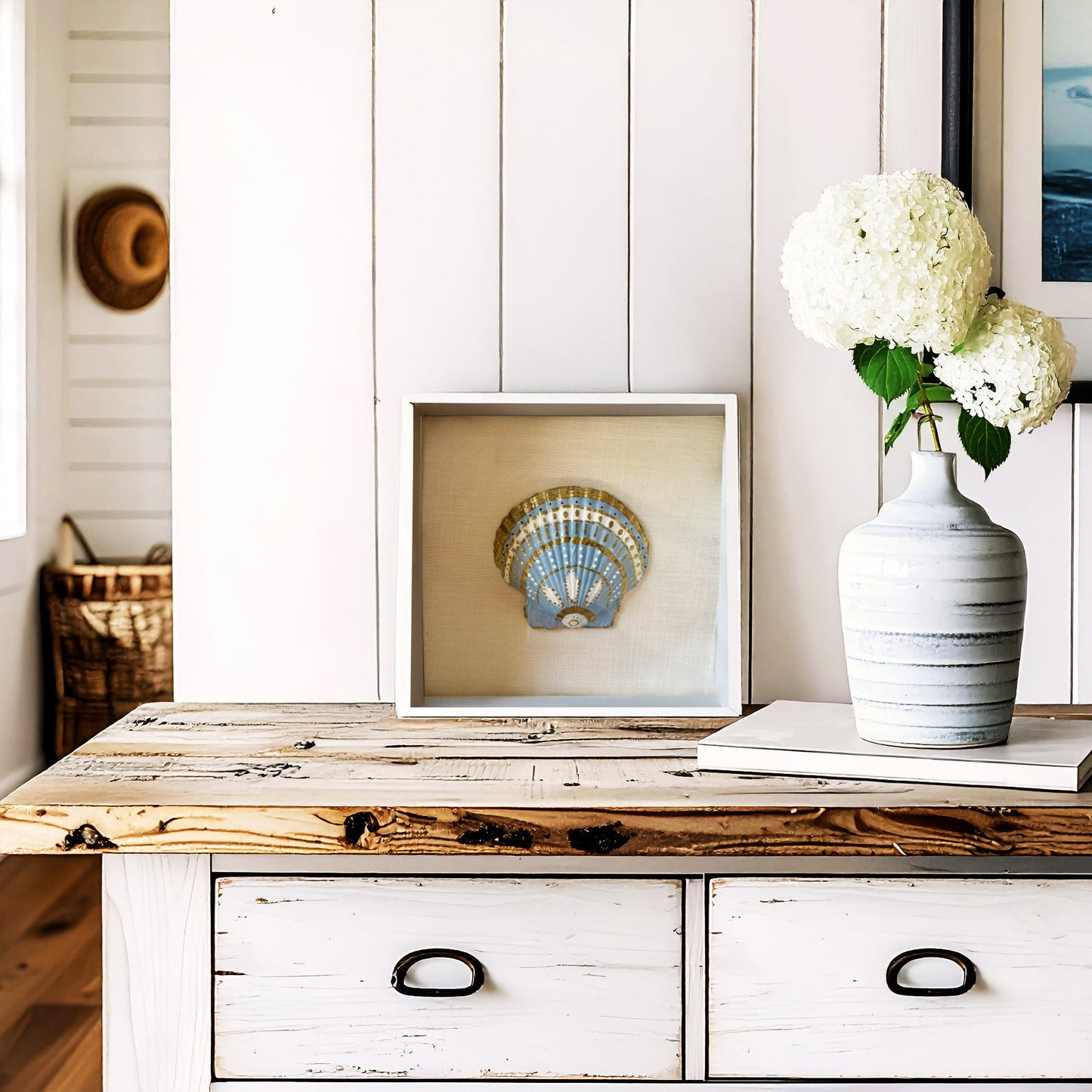 Wooden console table with a vase of flowers and framed picture against a white paneled wall.